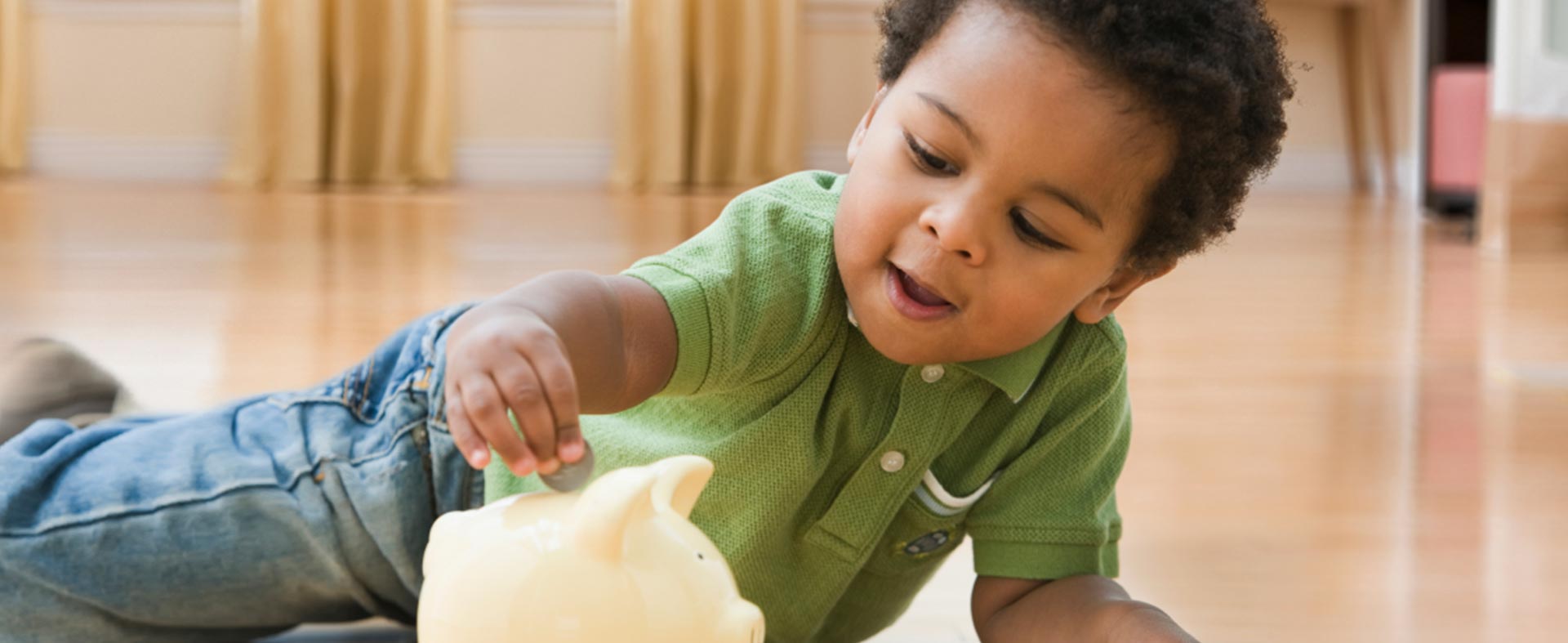 Toddler playing with coins and a piggy bank