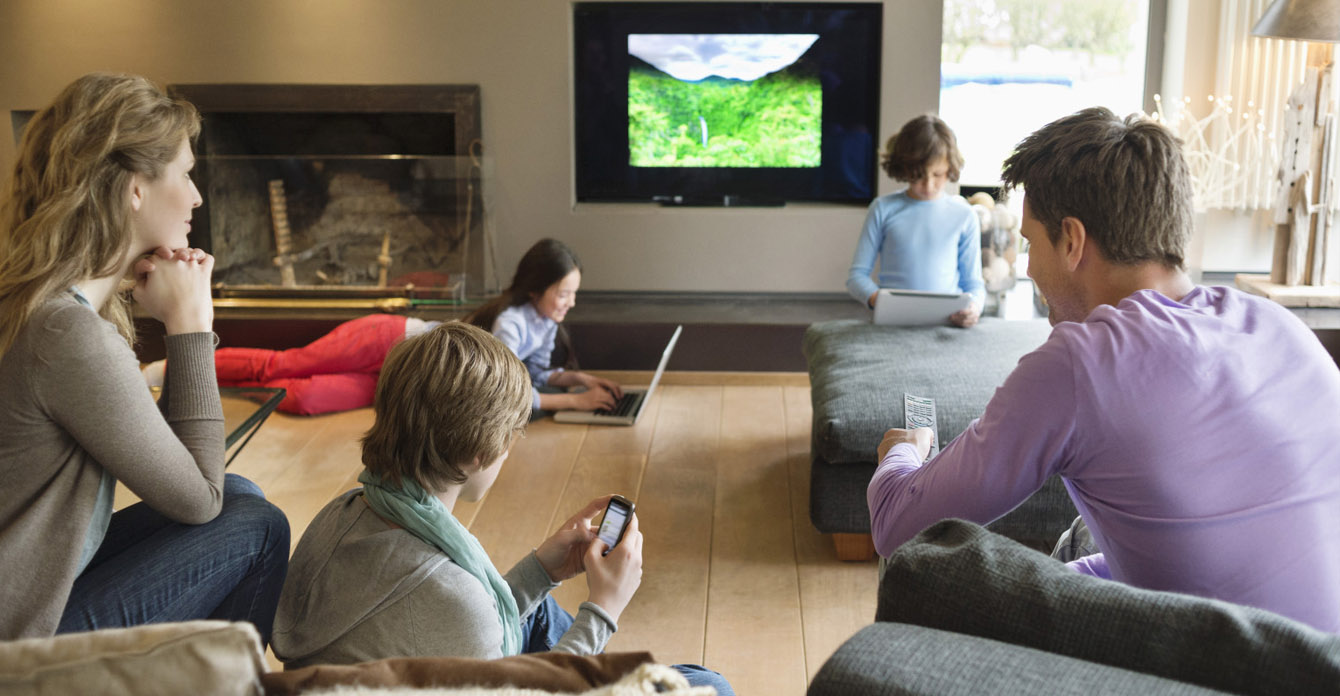 Family in the living room consuming digital media on devices