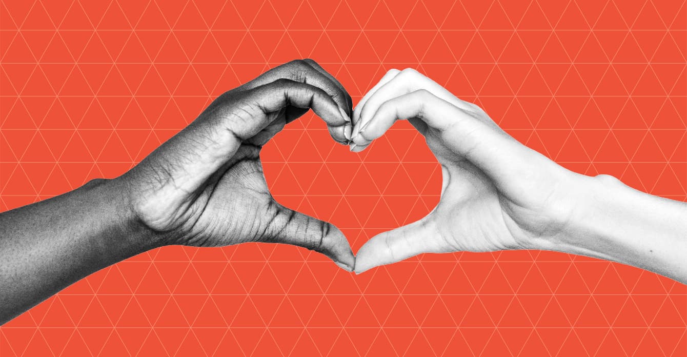 A black and white photo of two hands forming a heart shape against a red background with a subtle triangle pattern. The hands, one dark-skinned and the other light-skinned, symbolize unity and love.