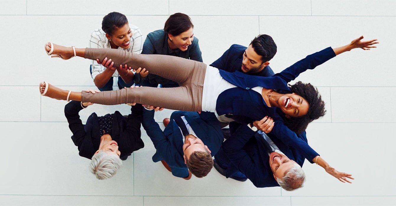 Businesswomen being lifted up by her coworkers in celebration