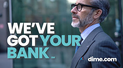 A man with gray hair and a beard, wearing glasses and a suit, stands confidently in front of a modern glass building. Large text reads 