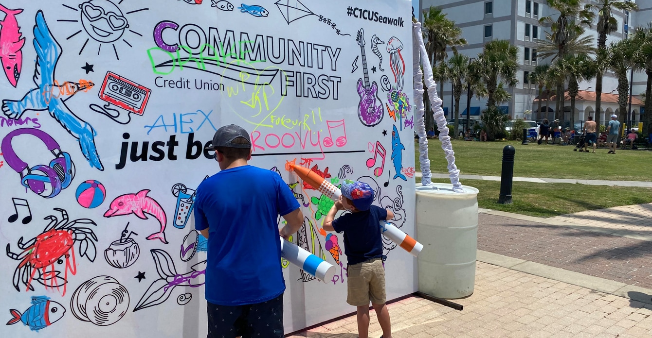 Father and son using oversized markers to color in a large coloring book style wall