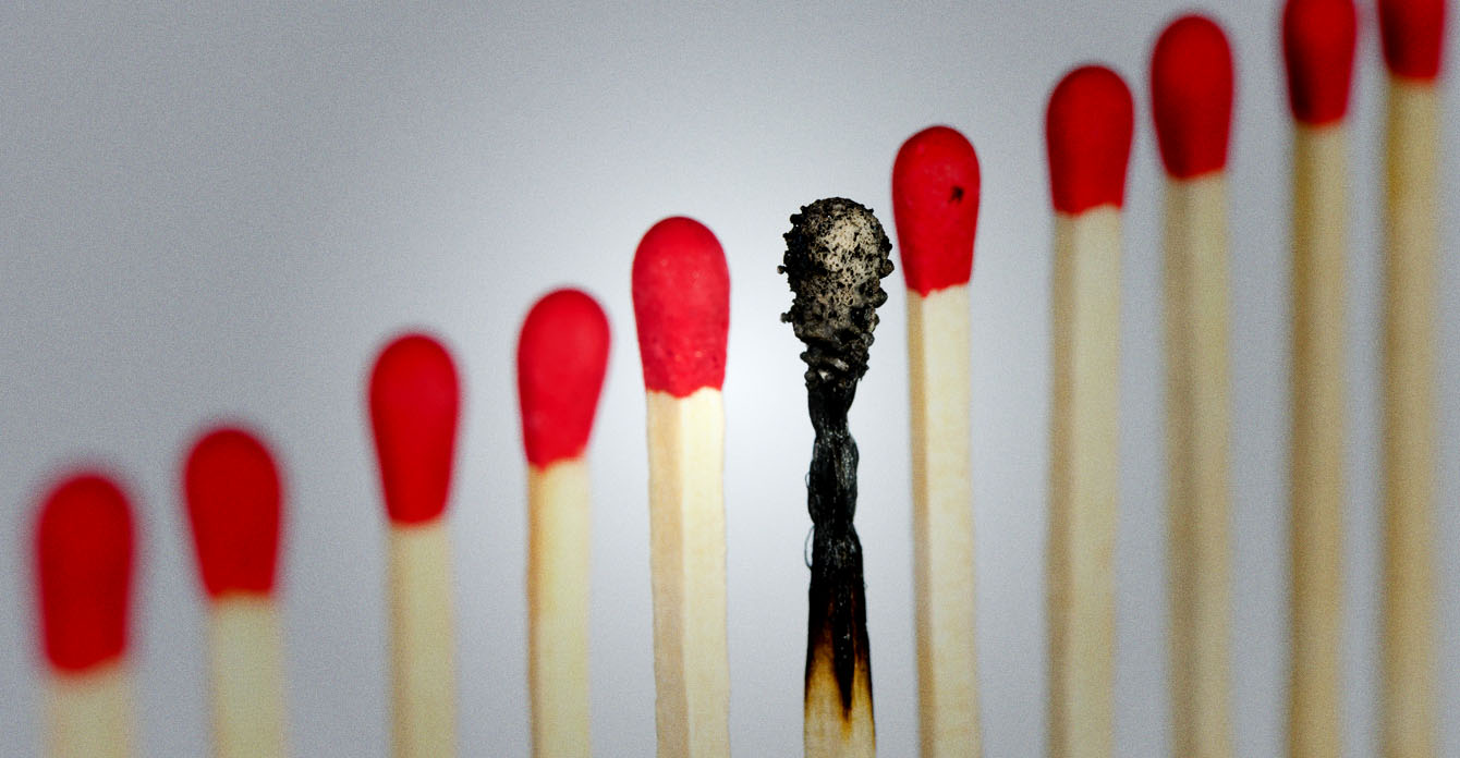 Photo of a single burnt match in a line of pristine ones.