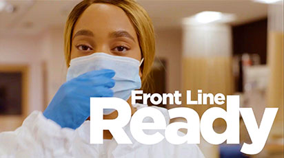 A healthcare worker adjusts their face mask while wearing blue gloves and a white protective suit. The background is a blurred hospital setting, and the text 
