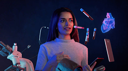 A woman living her story interacts with floating medical devices and holograms, including test tubes, a stethoscope, a smartphone, and a heart diagram against a dark background. She holds a smartphone and wears a light gray shirt.